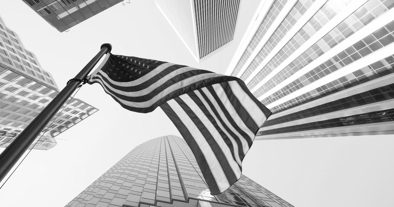 Black and white image of American flag surrounded by skyscrapers